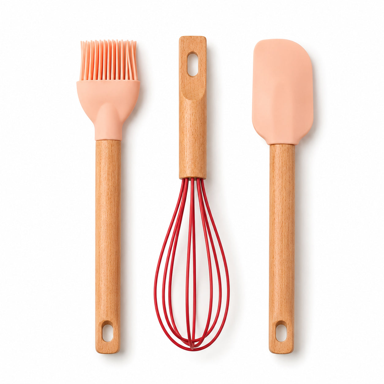 Three silicone kitchen utensils with light wood handles: a peach-colored pastry brush, a whisk with red wire, and a spatula with a peach-colored head, arranged vertically on a white background.