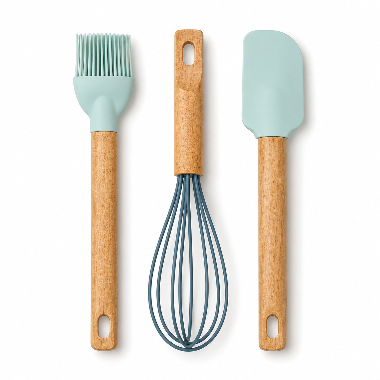 Three silicone kitchen utensils with light wood handles: a pastry brush with a mint green silicone head, a wire whisk with a slate blue wire body, and a spatula with a mint green silicone head, arranged vertically on a white background.
