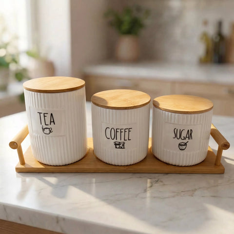 Three ceramic canisters labeled 'Tea', 'Coffee', and 'Sugar' with wooden lids on a marble surface.