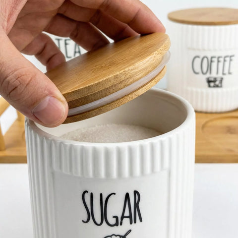 White ceramic sugar container with wooden lid, labeled 'SUGAR', on a white background.