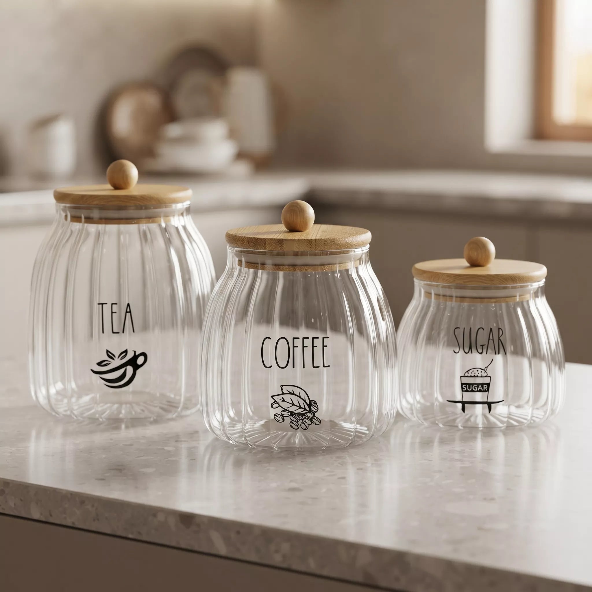 Three ribbed clear glass canisters with light wood lids and round wooden knobs, labeled TEA, COFFEE, and SUGAR, arranged on a marble kitchen counter.