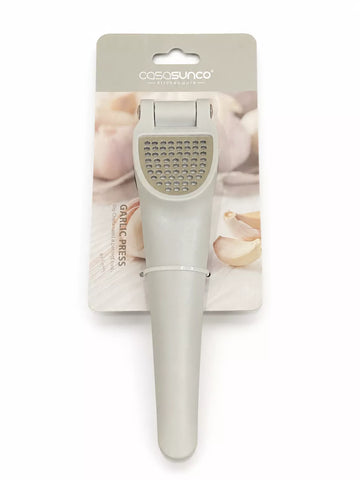 A light gray garlic press tool attached to a printed retail card, photographed on a plain white background. The card shows the brand name cosasunco and a photo of garlic cloves.