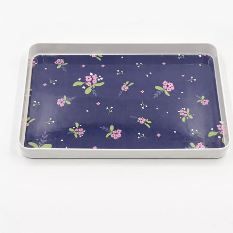 A rectangular metal tray with a navy blue floral patterned insert, photographed from a top-down angle on a white background.