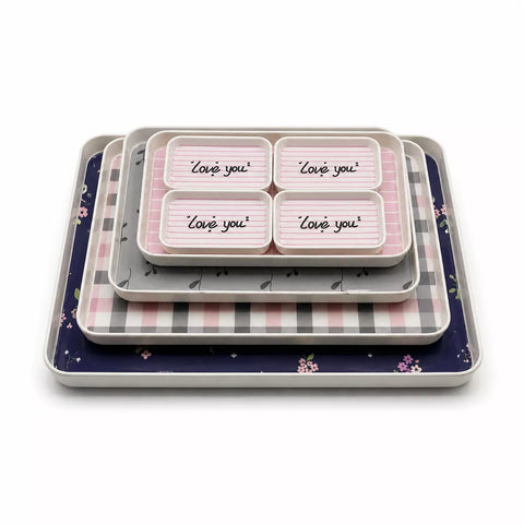A set of nested square trays with decorative patterns, including a navy blue floral tray, a pink and gray checkered tray, a gray tray, and a white tray with four compartments printed with 'Love you' in script.