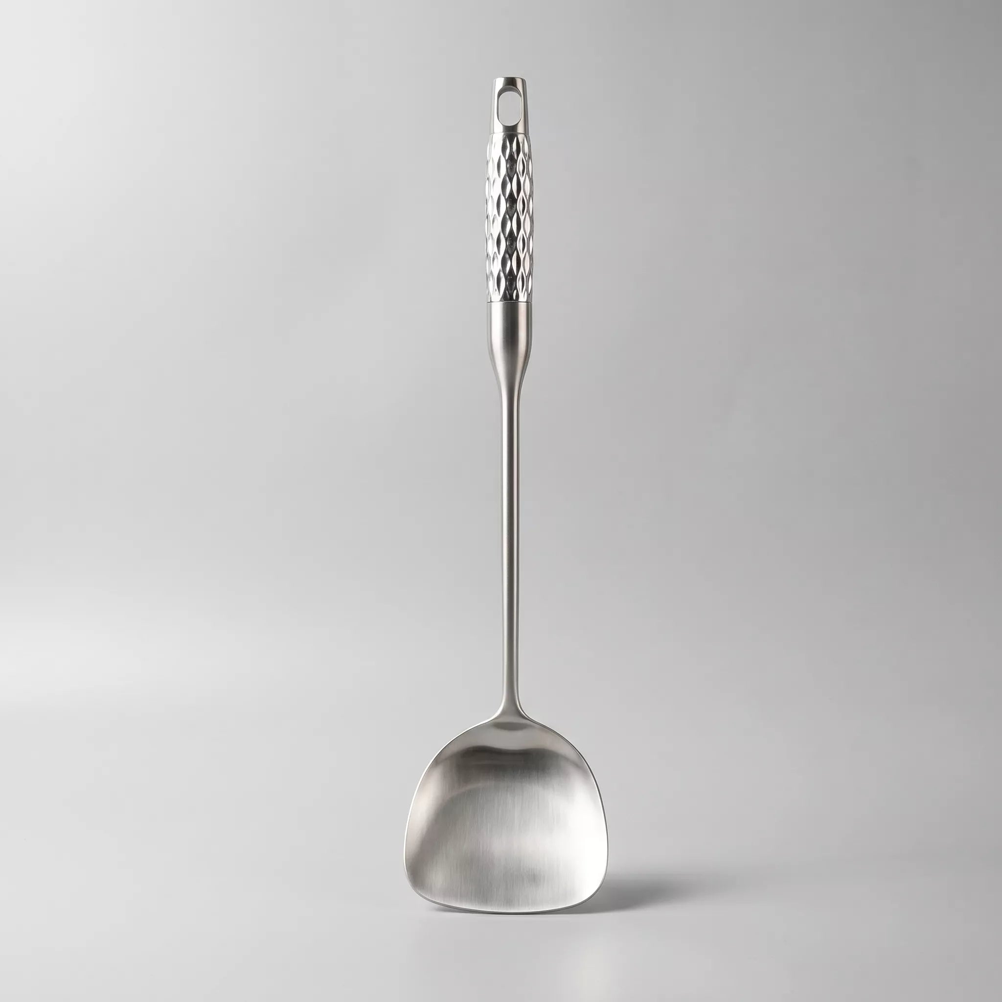Silver ladle with textured handle on a light gray background