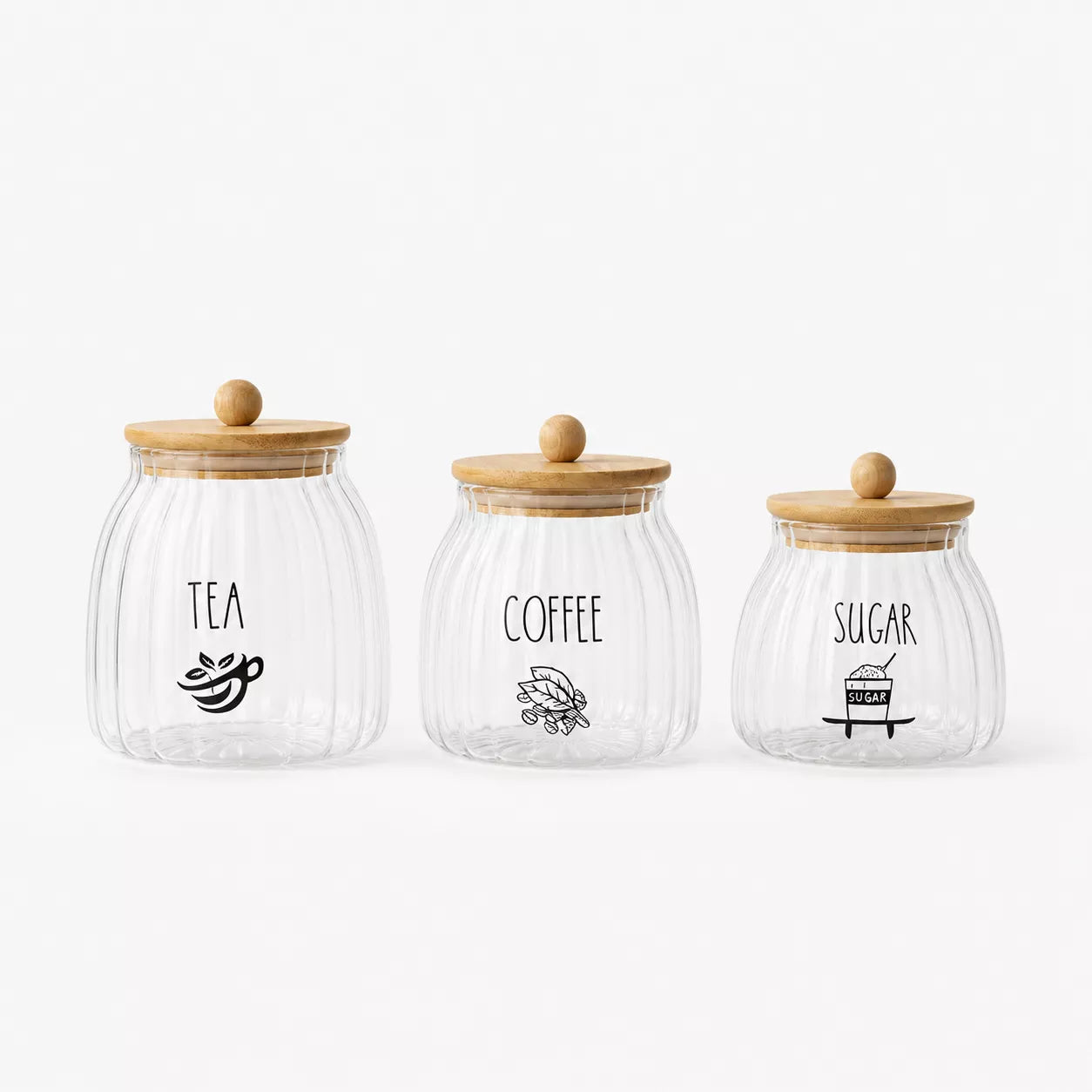 Three ribbed clear glass canisters with light wood lids and black printed labels for TEA, COFFEE, and SUGAR, arranged on a white background.